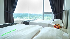 A hotel room with two beds, a large window with curtains, and a view of greenery. - Sri Beverly Hills Near KLIA & KLIA2 & F1 (Nilai)
