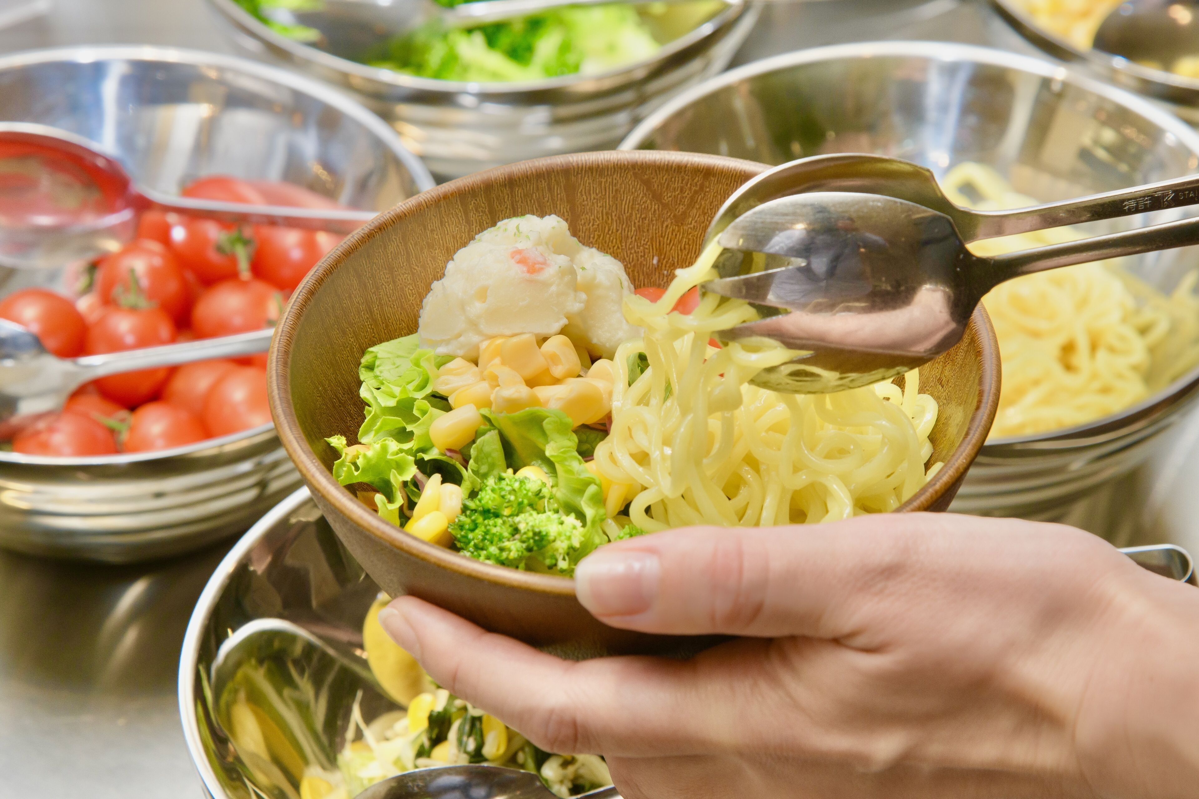 A bowl of pasta with vegetables and a spoon.