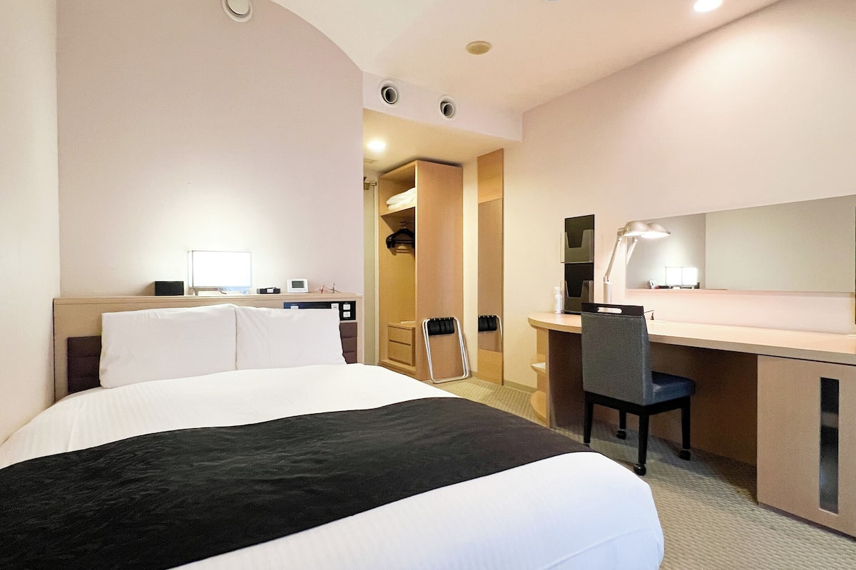 Ein Hotelzimmer mit Bett, Schreibtisch, Stuhl und Spiegel.