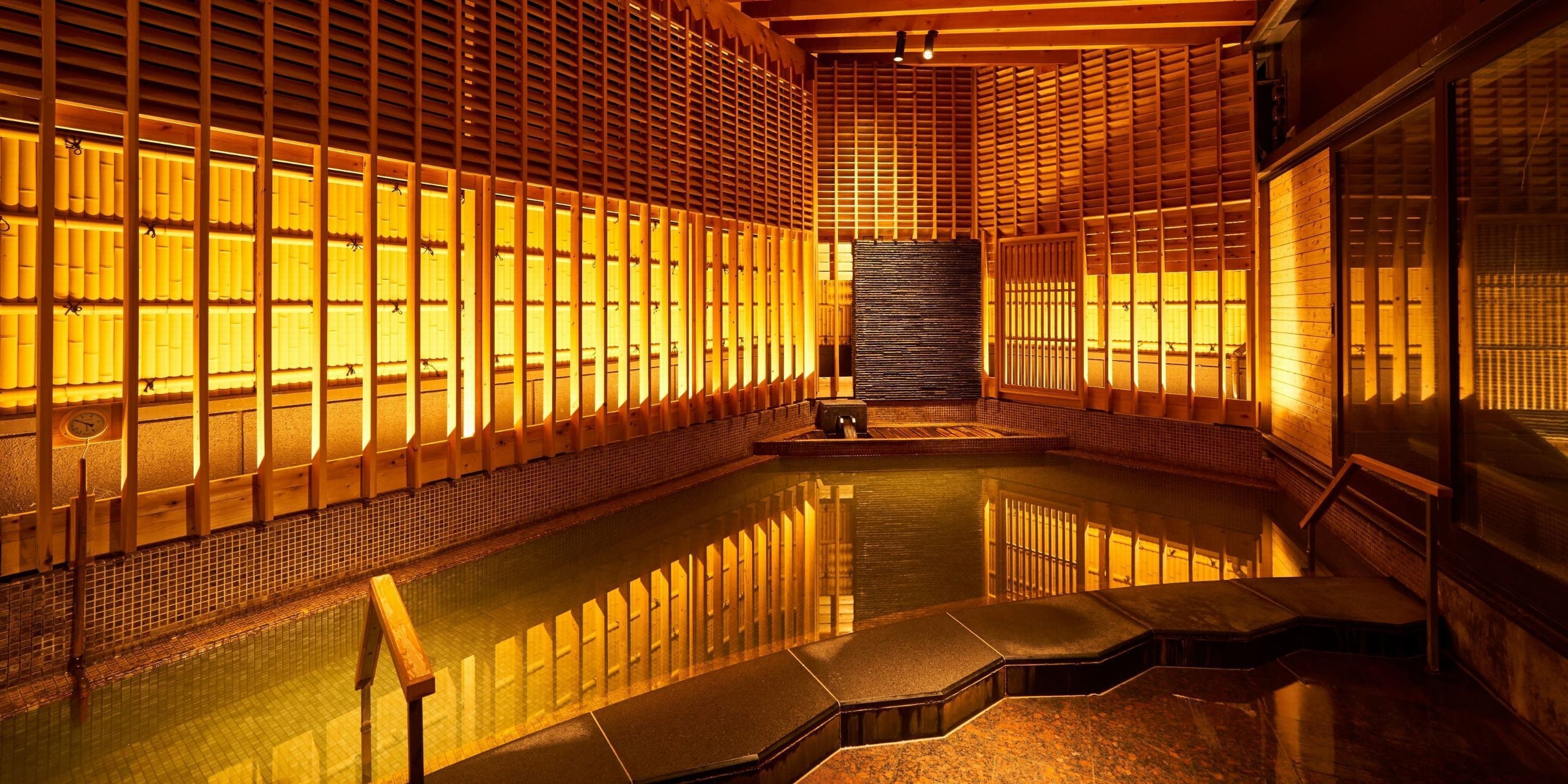 Un onsen japonés tradicional con puertas correderas de madera, una fuente termal central y paredes de azulejos.