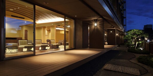 A modern hotel exterior at night with a well-lit outdoor seating area and a pathway leading to the entrance. - Hakodate Hotel Banso(ORIX HOTELS & RESORTS) (Hakodate)