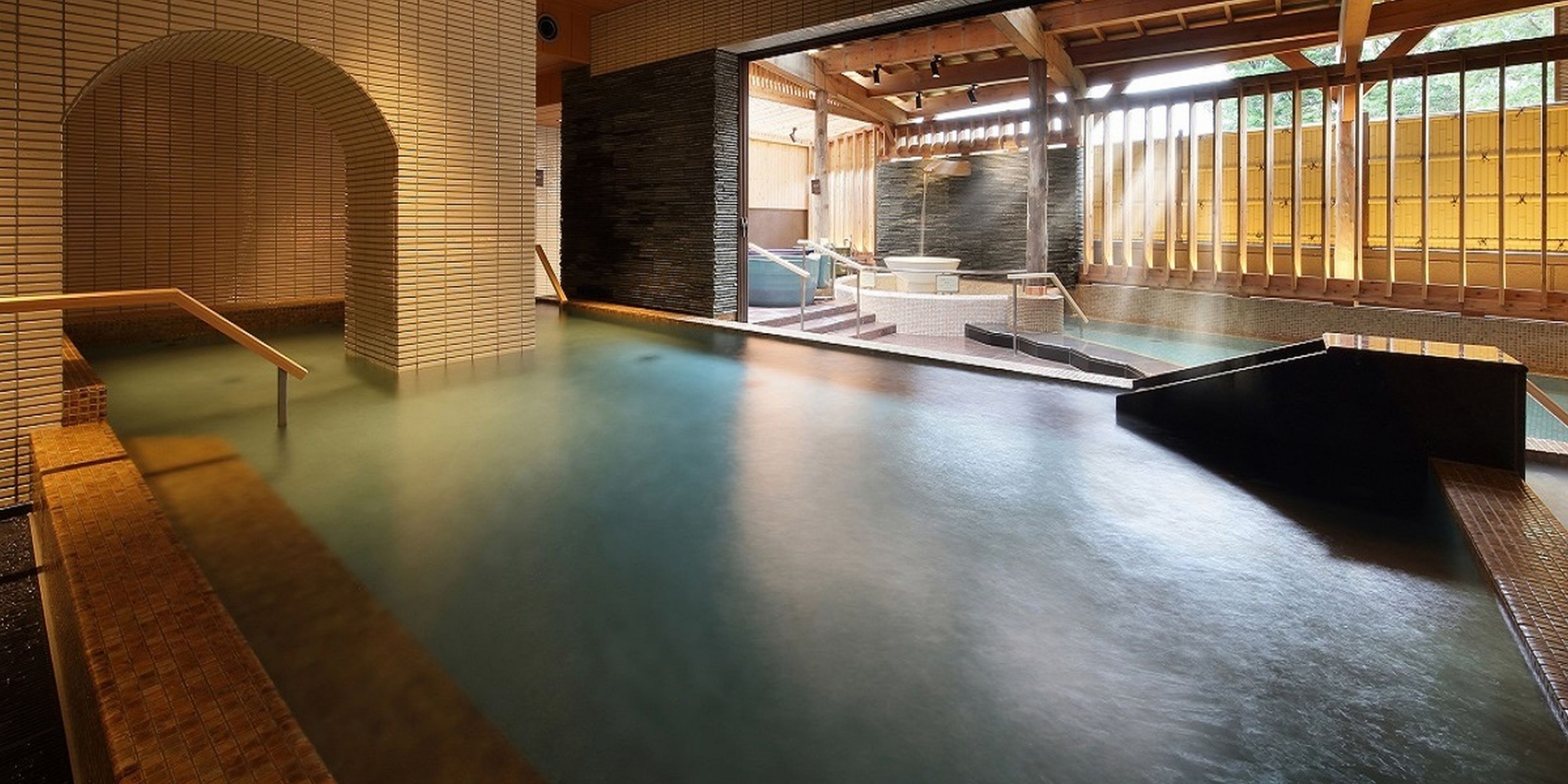 Un jacuzzi con terraza de madera, pared de piedra y vistas al exterior.