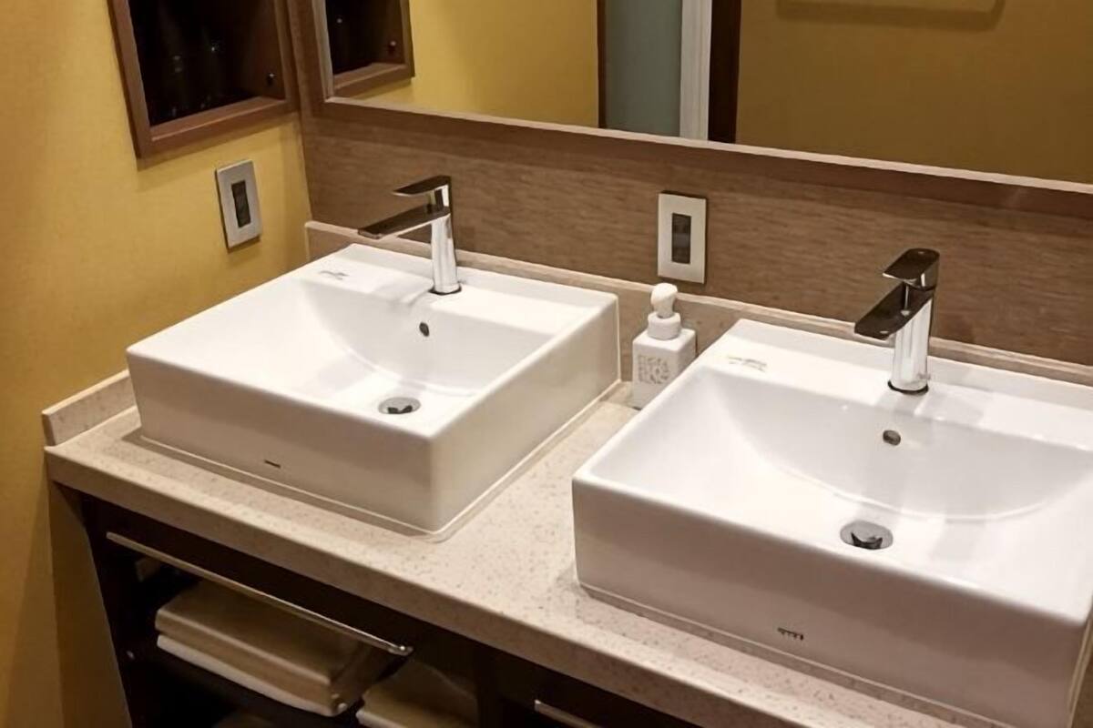 A bathroom with two white sinks, a mirror, and a towel rack.