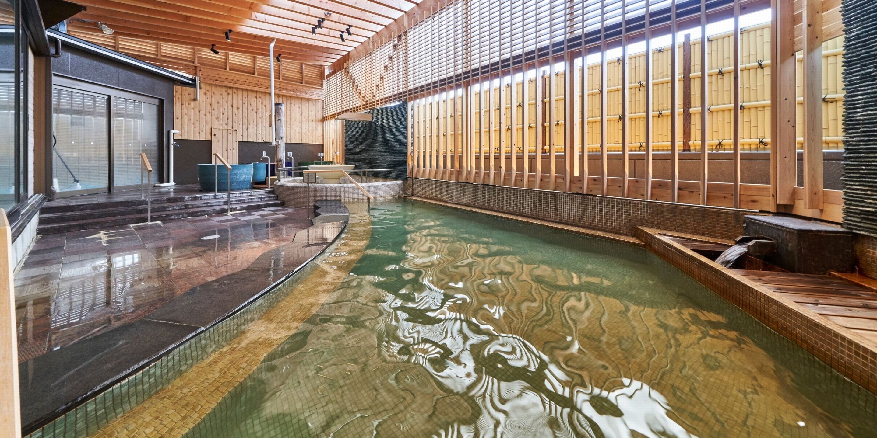 Una amplia piscina interior con cubierta de madera y una barrera de vidrio.