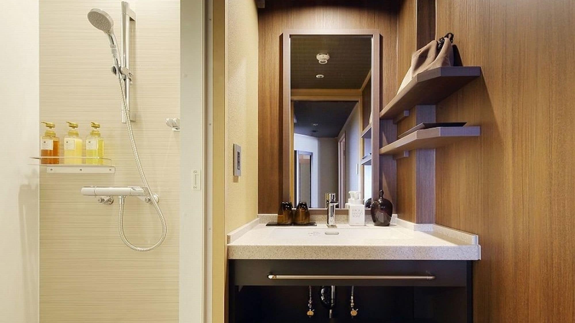 A modern bathroom with a shower, a vanity with a mirror, and a wooden shelf with toiletries.