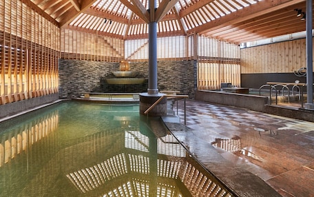 A spa with a large indoor pool, wooden beams, stone walls, and a stone fireplace.