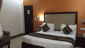 A hotel room with a large bed, a nightstand, a chair, and a door.