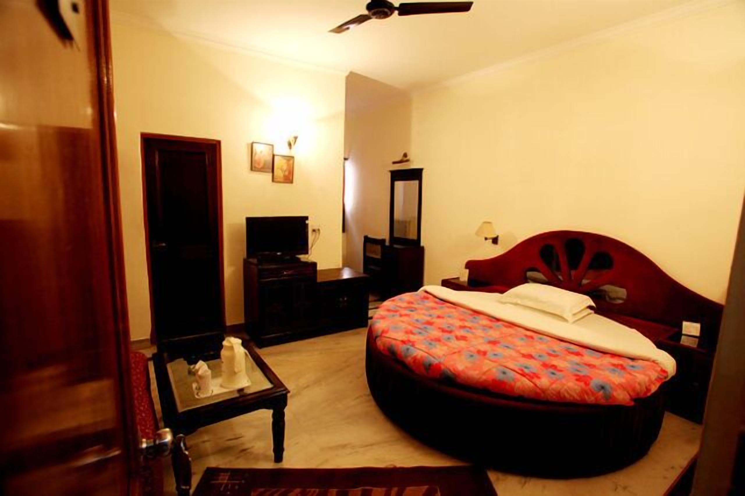 Un dormitorio con cama, escritorio, silla, espejo y ventilador de techo.