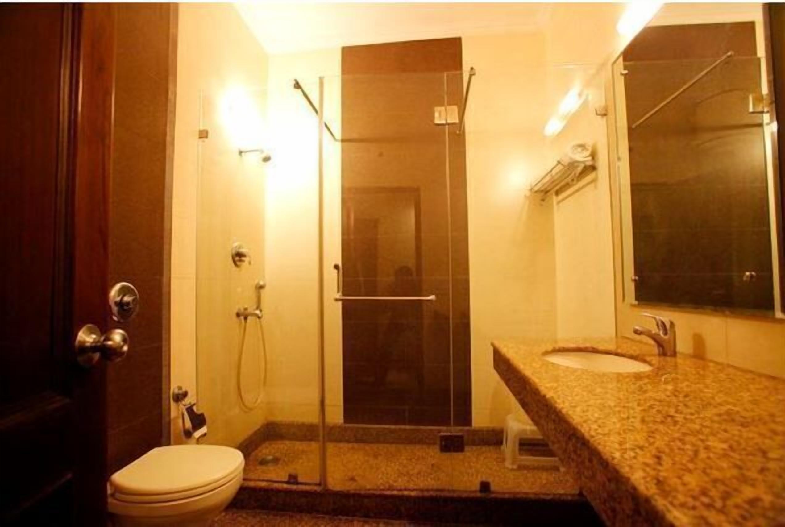 A bathroom with a glass-enclosed shower, a toilet, and a sink with a mirror.