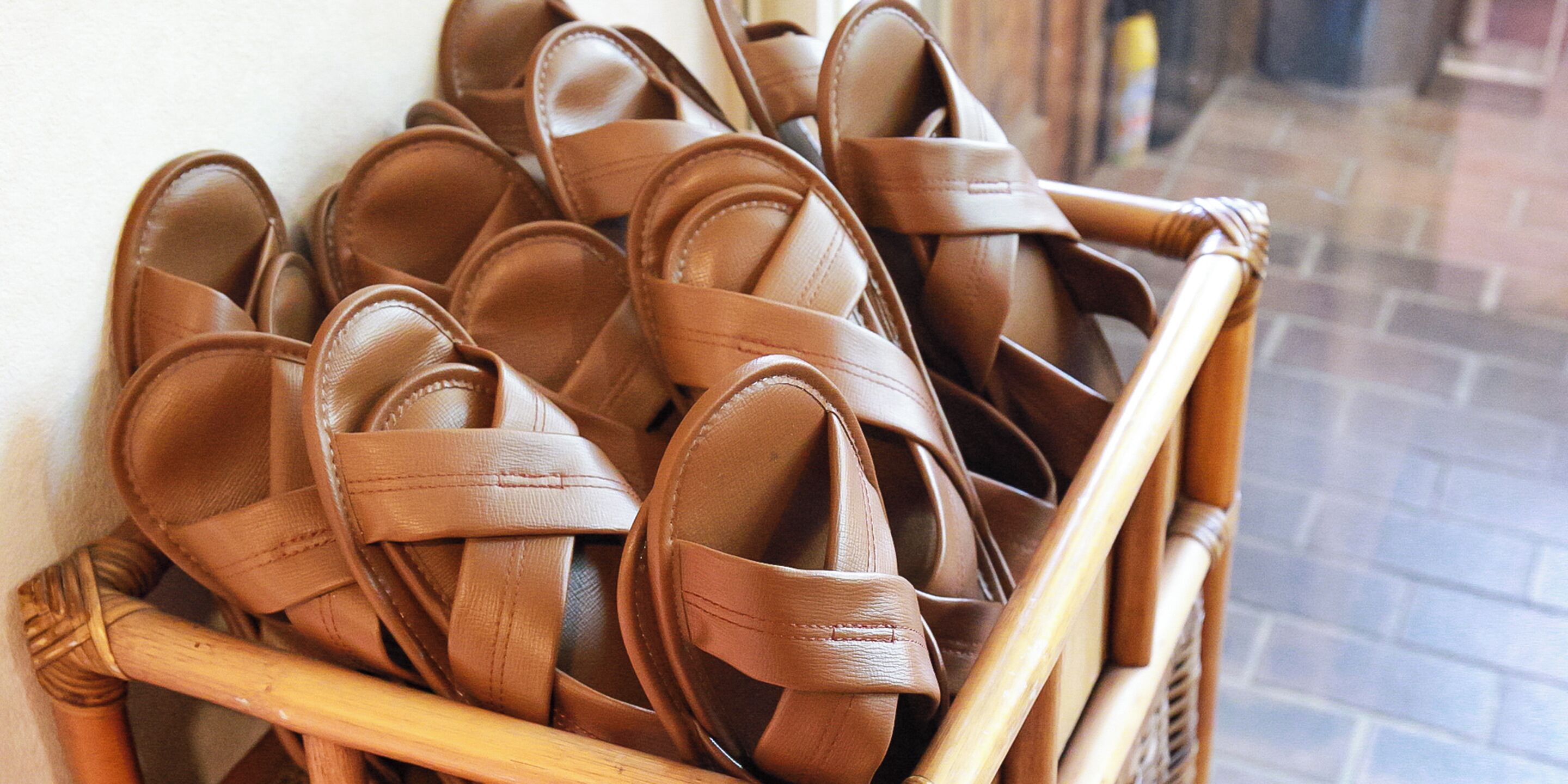 A wicker basket filled with brown sandals.