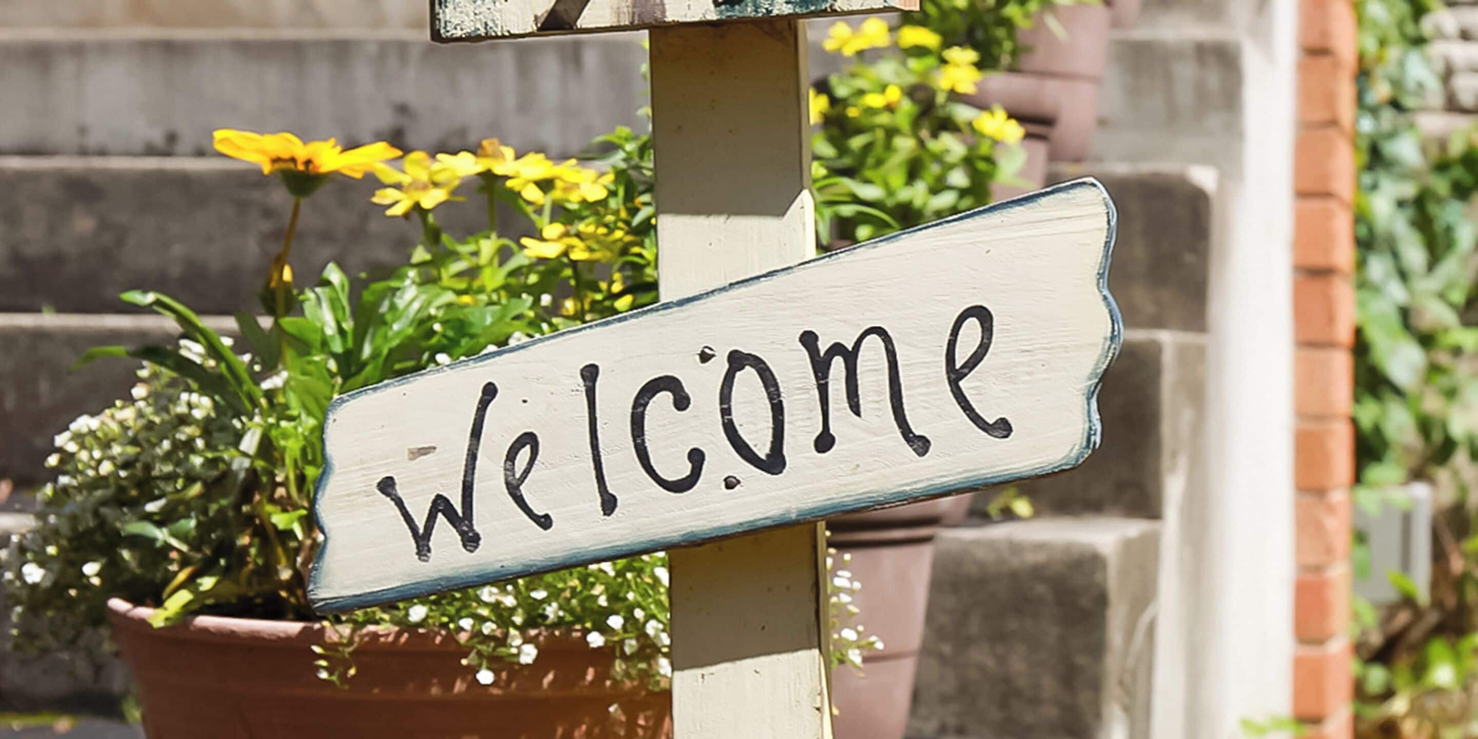 A wooden welcome sign with the word "Welcome" on it.