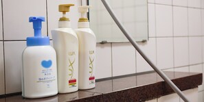 Tres botellas de jabón Lux sobre un repisa de azulejos.