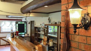 Una zona de bar con mostrador de madera, pared de ladrillo y una lámpara colgante.