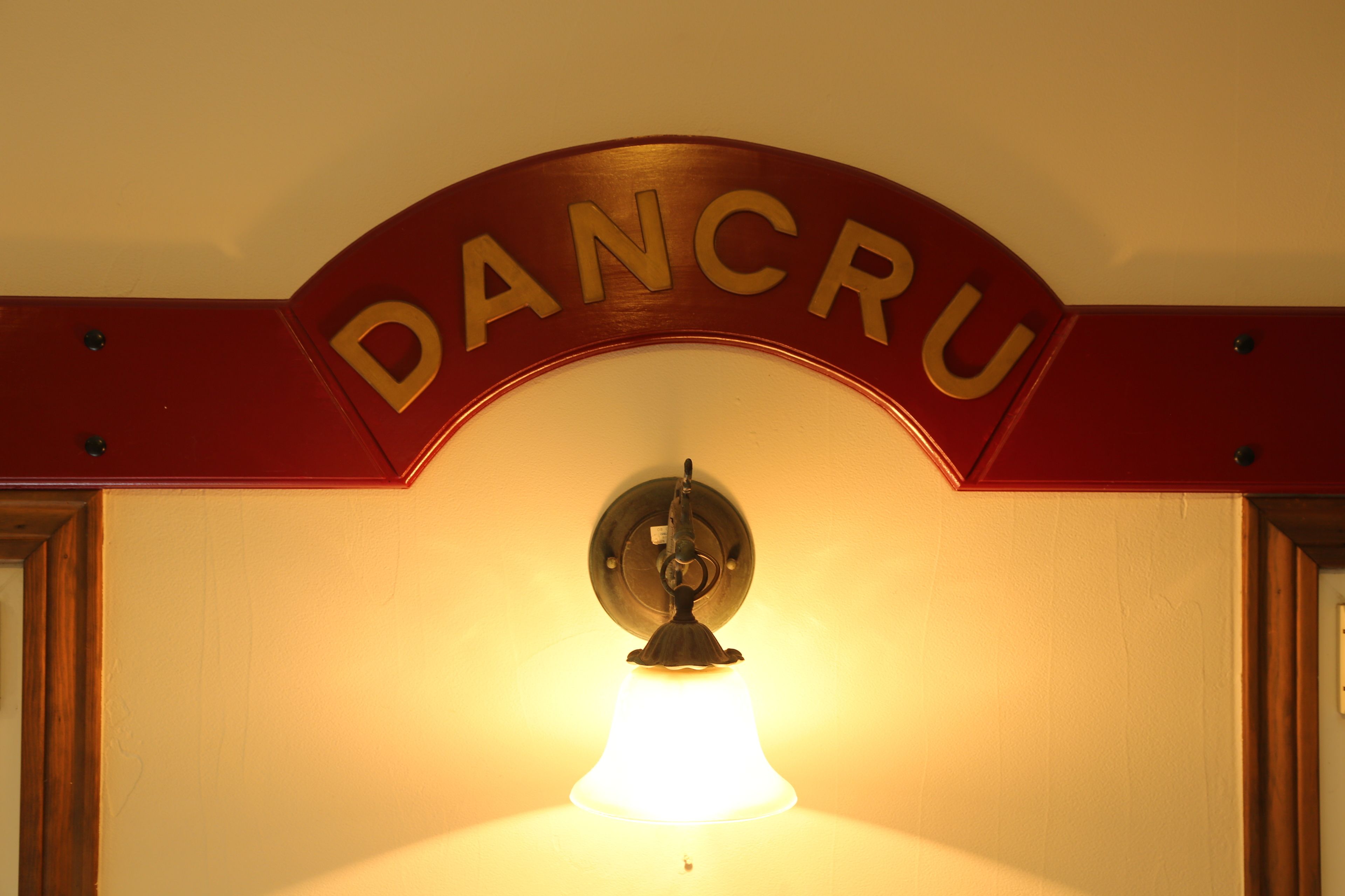 A wall-mounted light fixture with the name "DANCRU" above it.