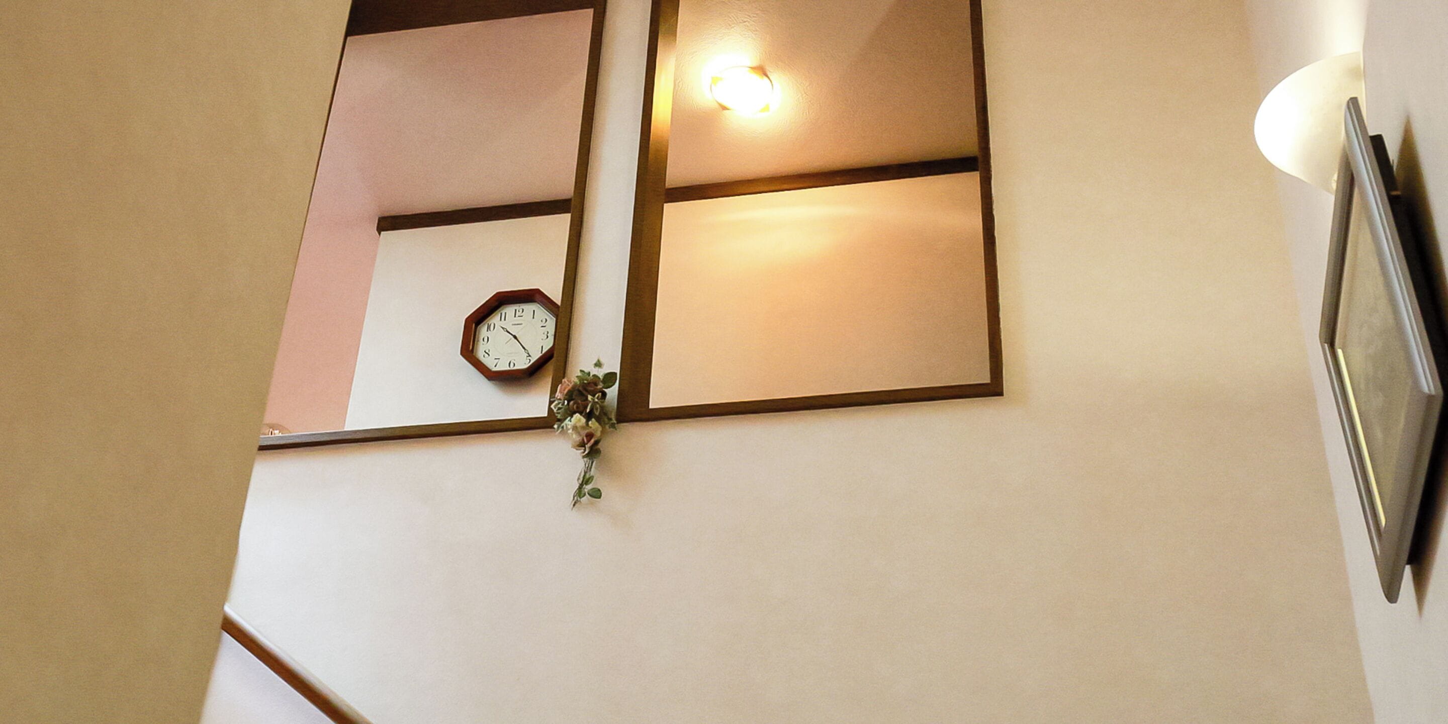 A wall with a clock, a light fixture, and a framed picture.