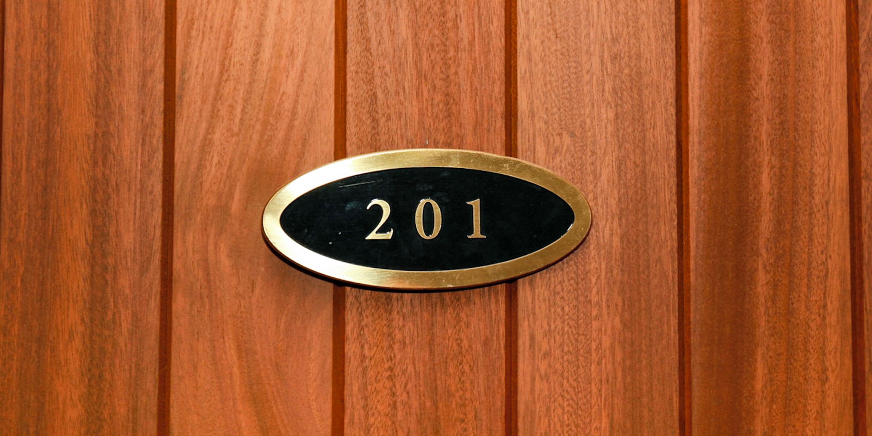 Una placa con el número de habitación en una puerta de madera.