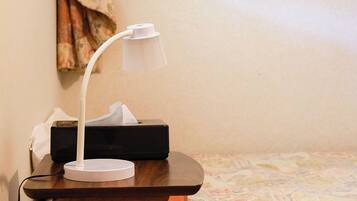 A desk lamp on a wooden table with a tissue box and a black electronic device in the background.