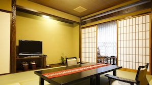A traditional Japanese room with tatami flooring, a low table, a television, and sliding doors.