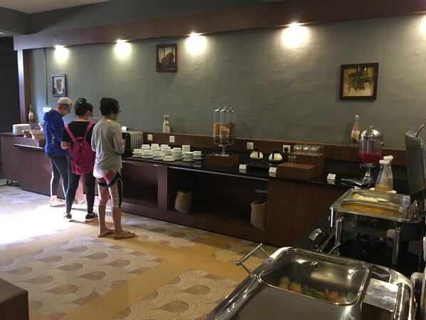Zona de bufé con mostrador, recipientes para alimentos y dispensador de bebidas.