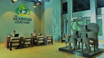 Check-in at The Mountain Courtyard, where friendly staff welcome guests at the reception desk, surrounded by a beautiful floral arrangement and a striking elephant sculpture.