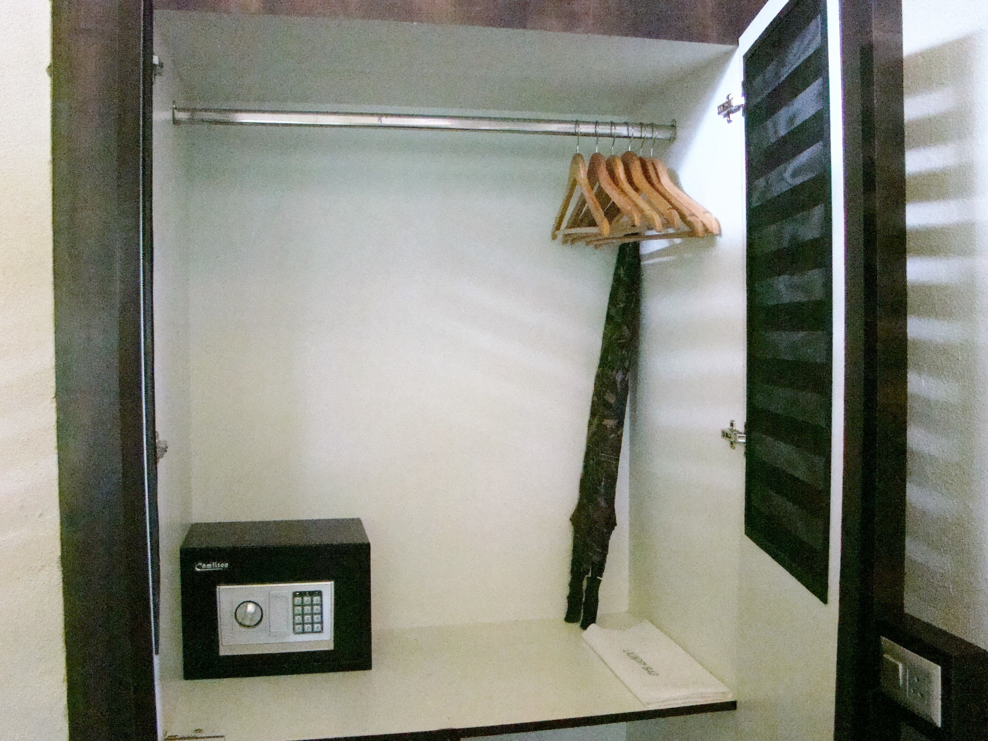 A walk-in closet with a black safe, a hanging rack, and a mirror.