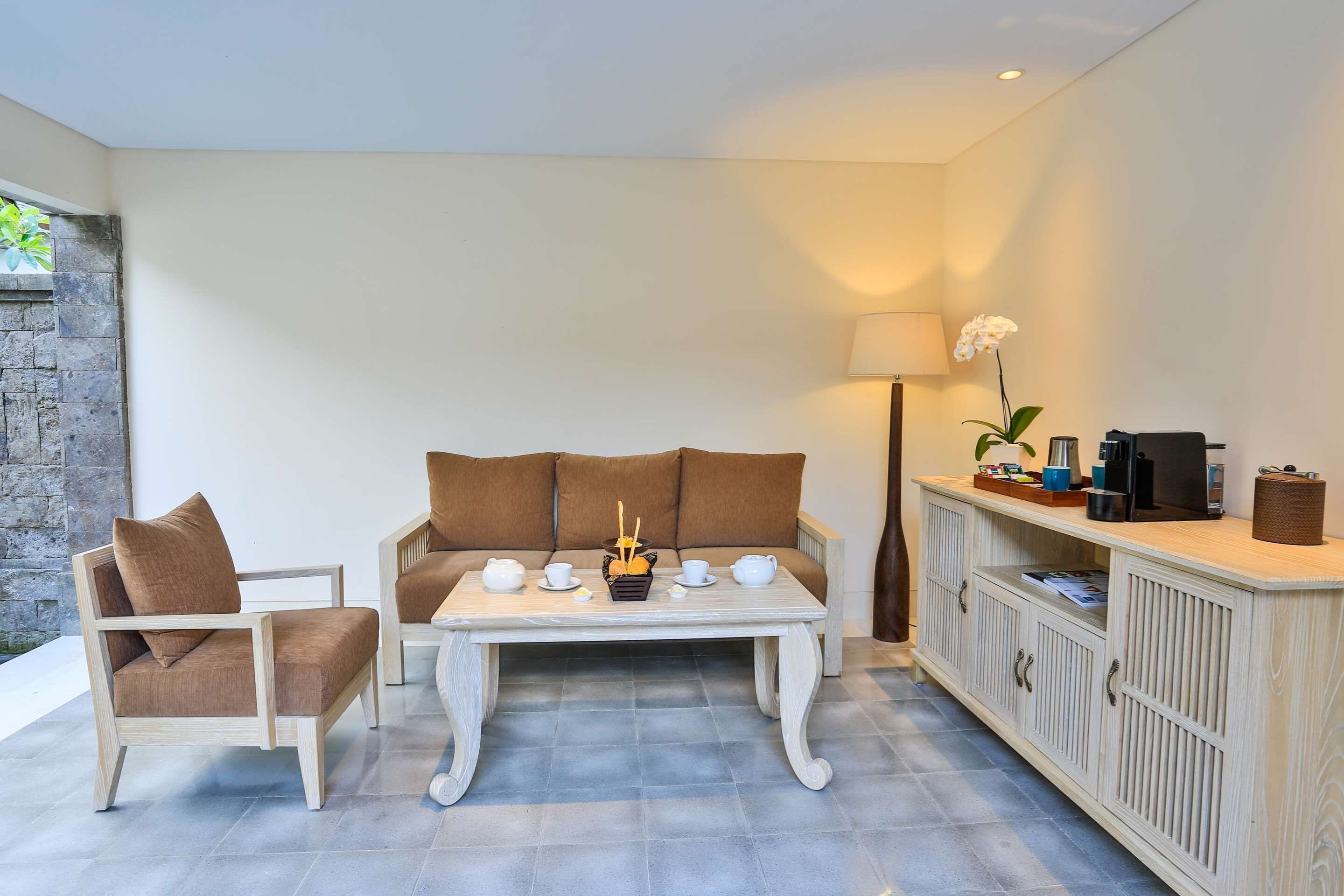 A living area with a sofa, armchair, and coffee table, a lamp, and a cabinet with storage.
