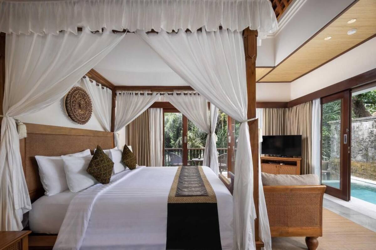 A bedroom with a canopy bed, a television, and a view of a pool.