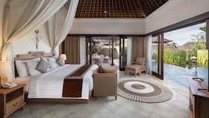 A spacious bedroom with a large bed, a sitting area with a view of a water body, and a dining area. - Visesa Ubud Resort (Ubud)