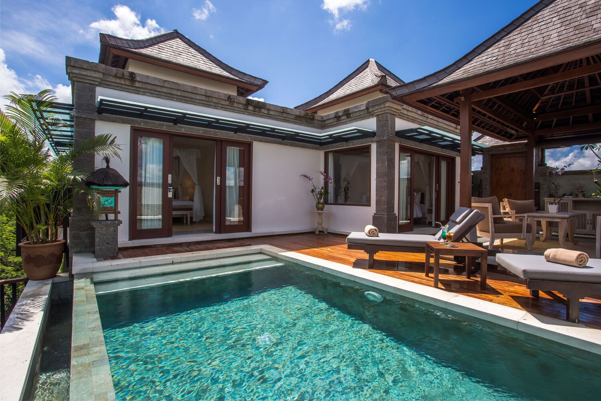 A modern villa with a swimming pool, outdoor seating, and a covered patio area.