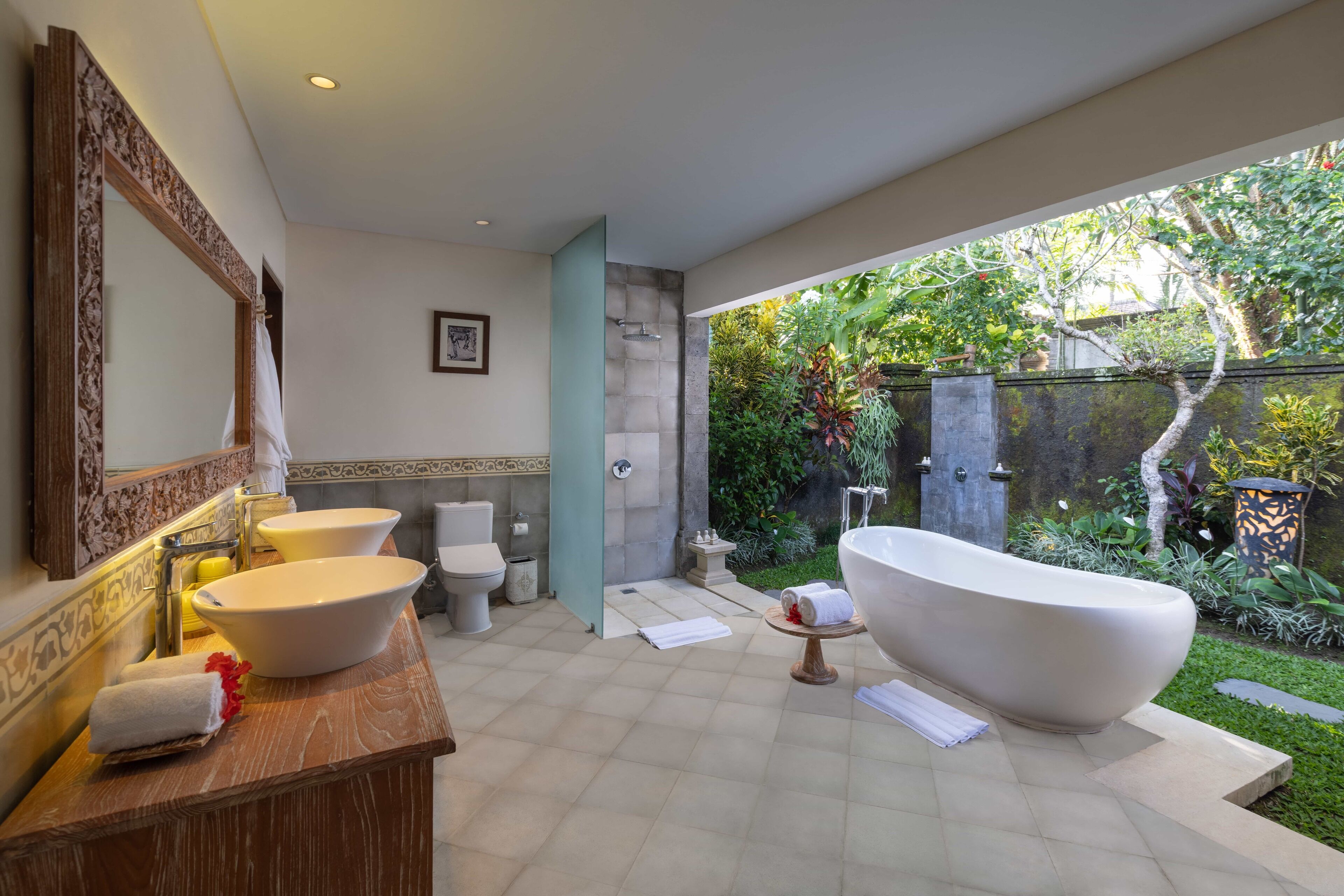 Un baño moderno con una bañera independiente, dos lavamanos y un espejo grande.