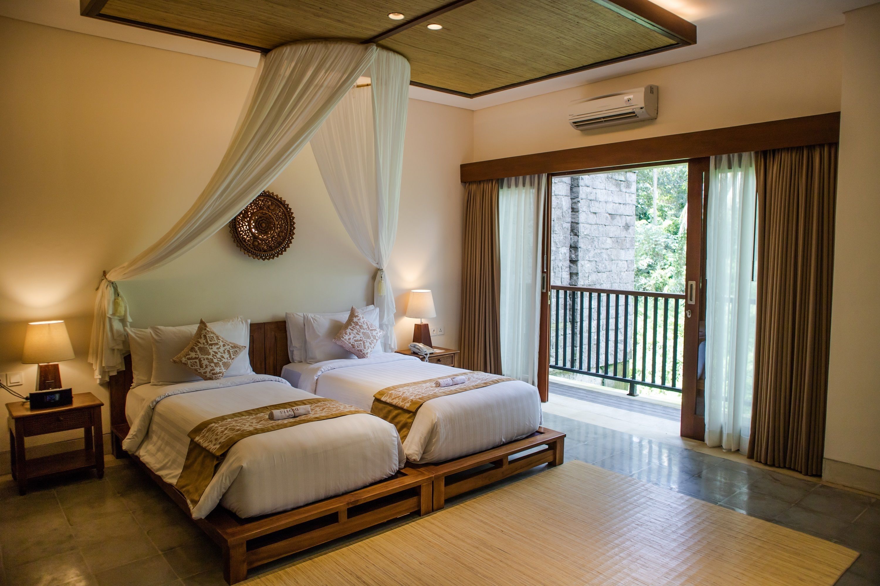 A double bed with a canopy, bedside tables with lamps, and a view of a balcony.
