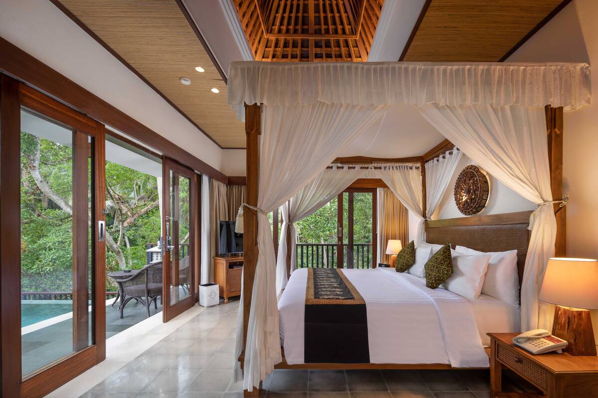 A spacious bedroom with a large bed, a canopy, and a view of the outdoors.