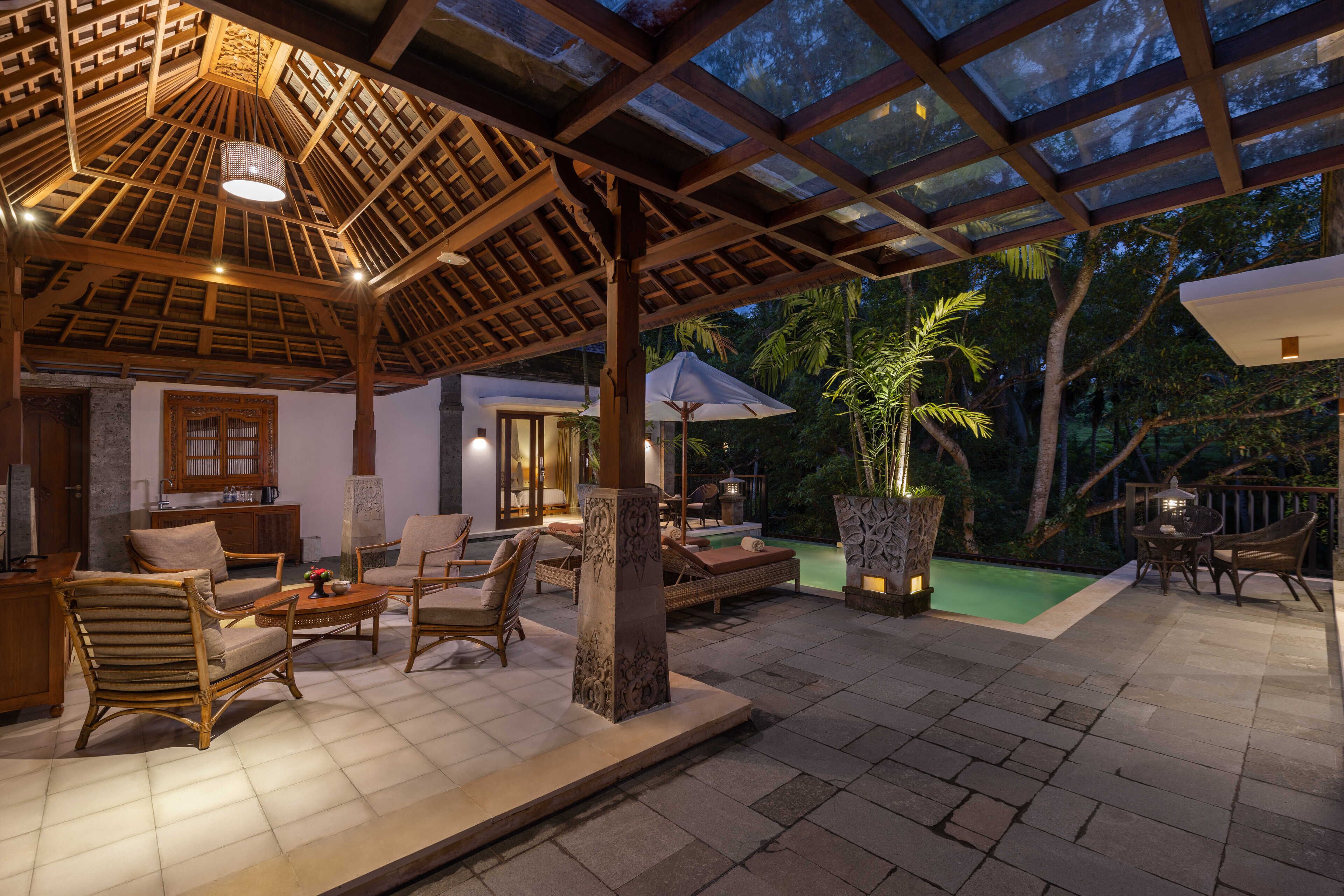 An outdoor patio area with wooden furniture, a pool, and a covered seating area.
