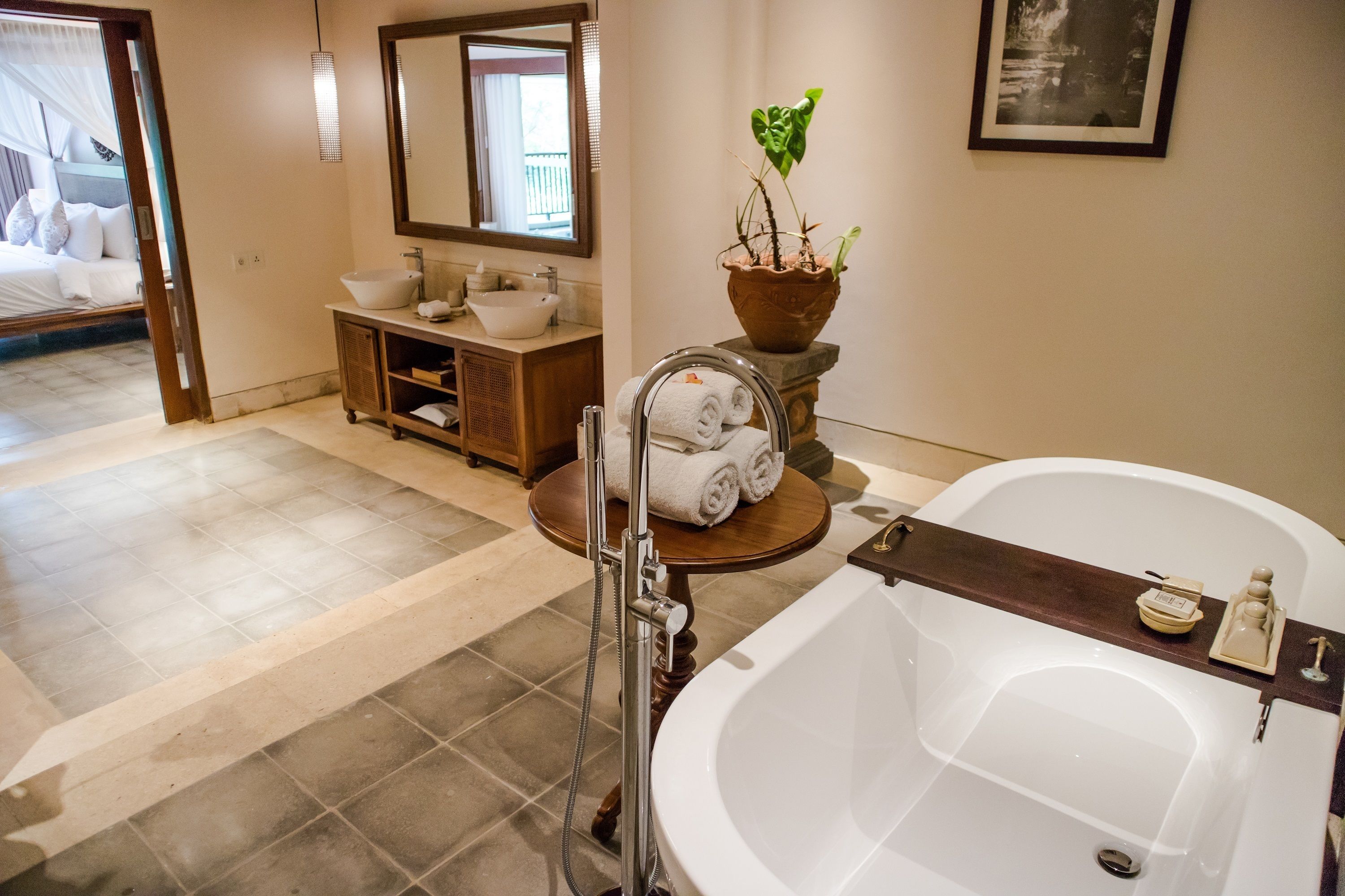Un baño con bañera, lavabo, tocador y una planta en maceta.