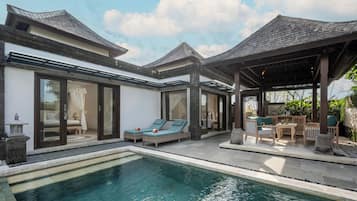 A modern resort with a pool, lounge chairs, and a covered patio area.
