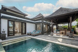 A modern resort with a pool, lounge chairs, and a covered patio area.