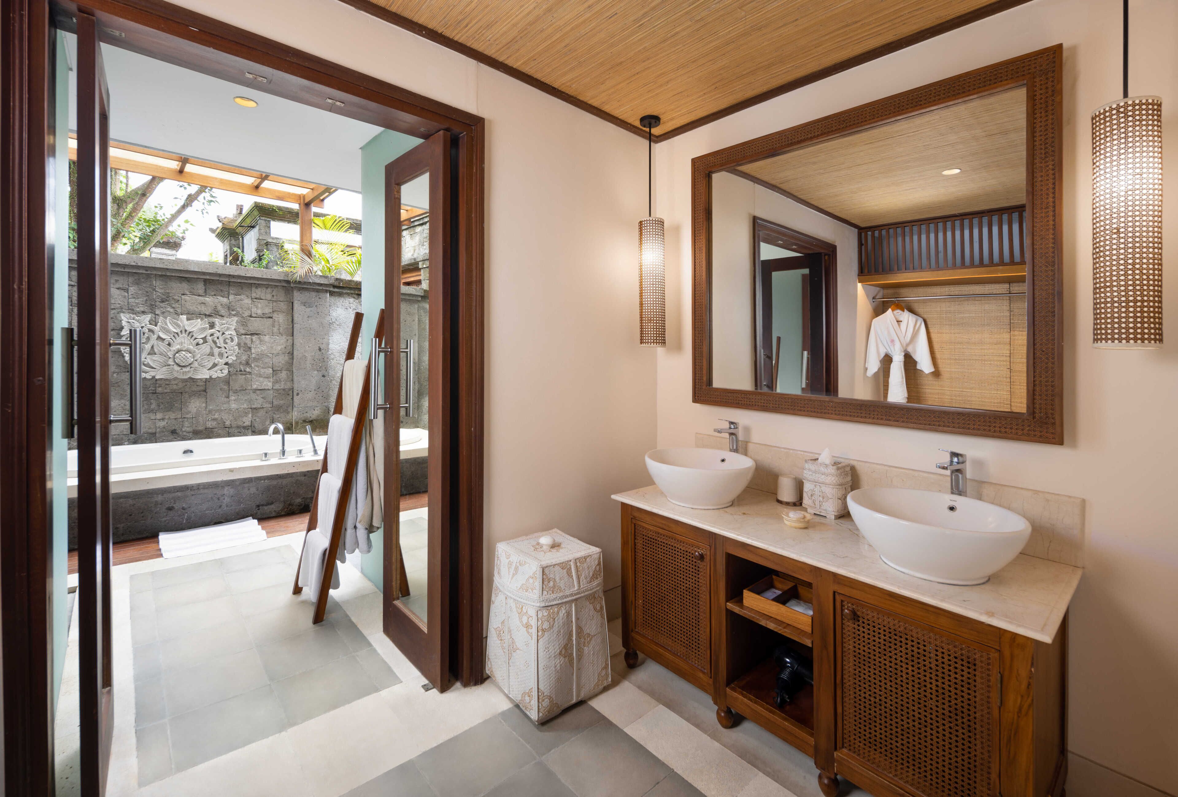 Un baño moderno con un espejo grande, dos lavamanos y una bañera.