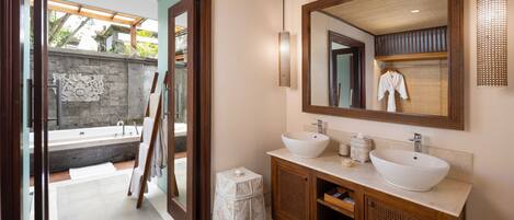 A modern bathroom with a large mirror, two sinks, and a bathtub.