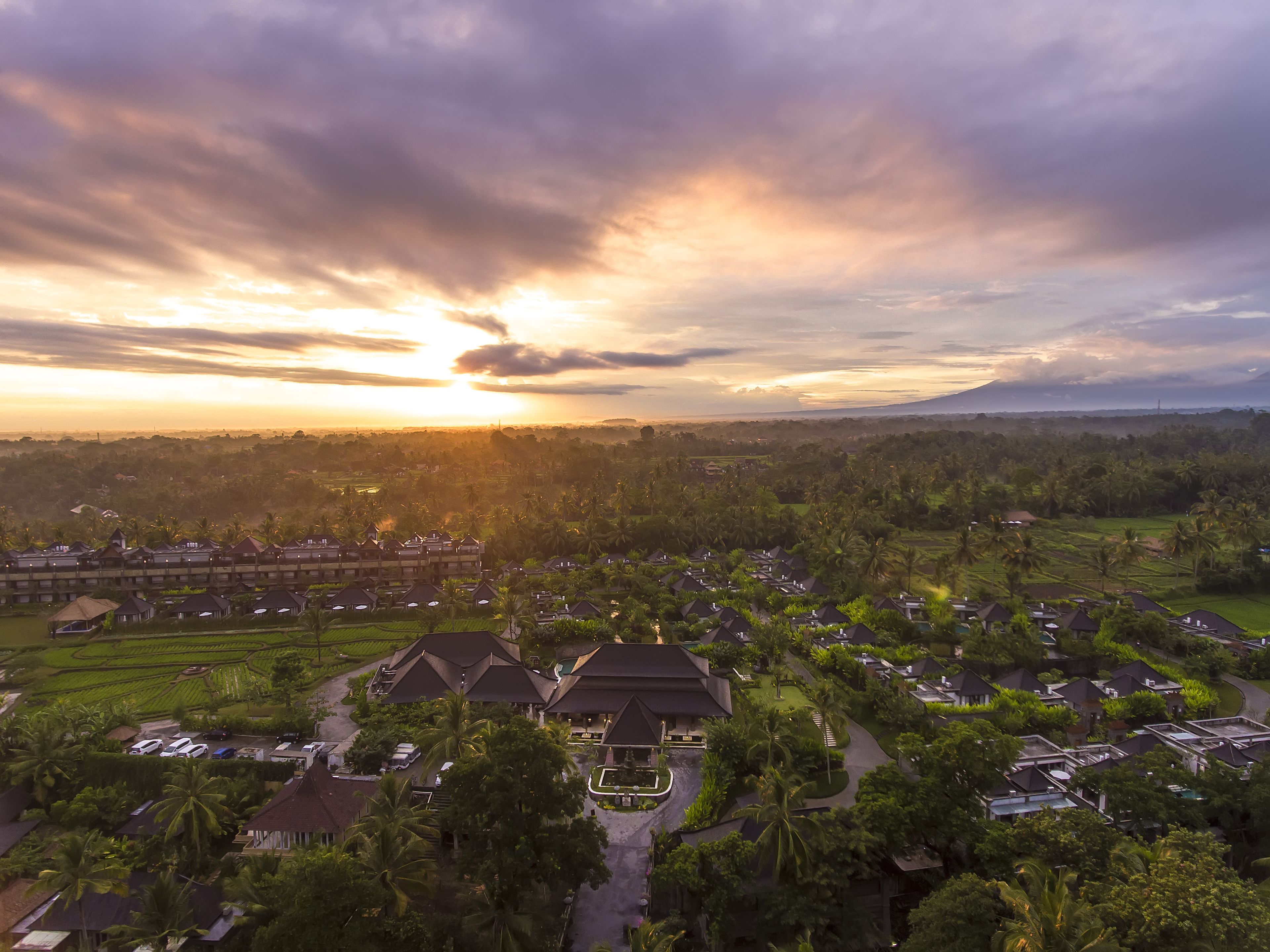 A resort with multiple bungalow-style buildings, a central pool area, and surrounding lush greenery.