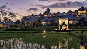 A resort with multiple thatched-roof cottages, a central gazebo, and terraced rice fields. - Visesa Ubud Resort (Ubud)