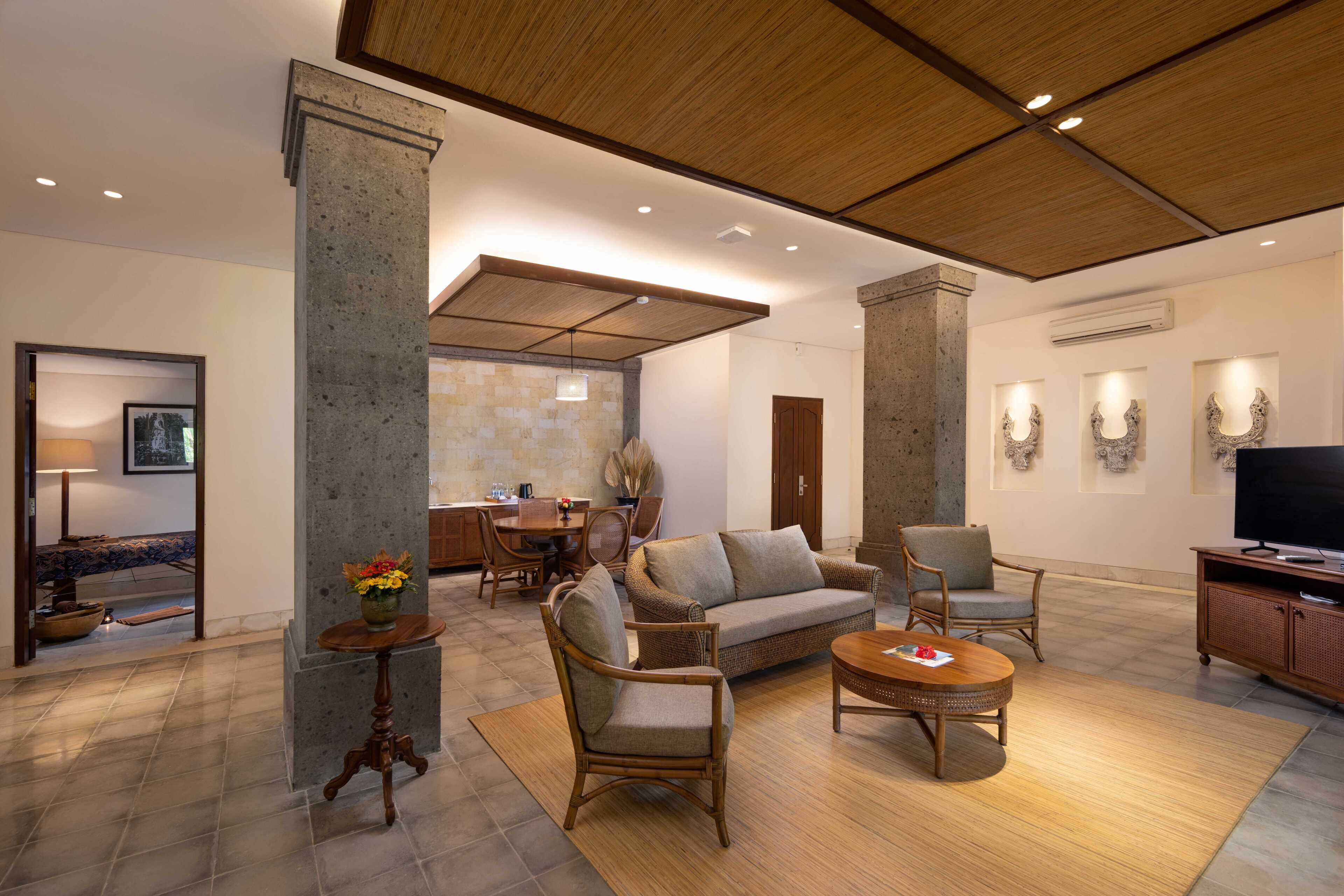 A spacious living area with a high ceiling, a dining table, sofas, and a television.
