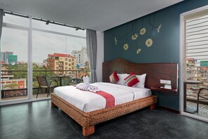 A hotel room with a large bed, a balcony with a table and chairs, and a city view. - Monsoon Bassac Hotel (Phnom Penh)