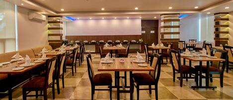 A spacious dining area with multiple tables and chairs, arranged in a symmetrical layout.
