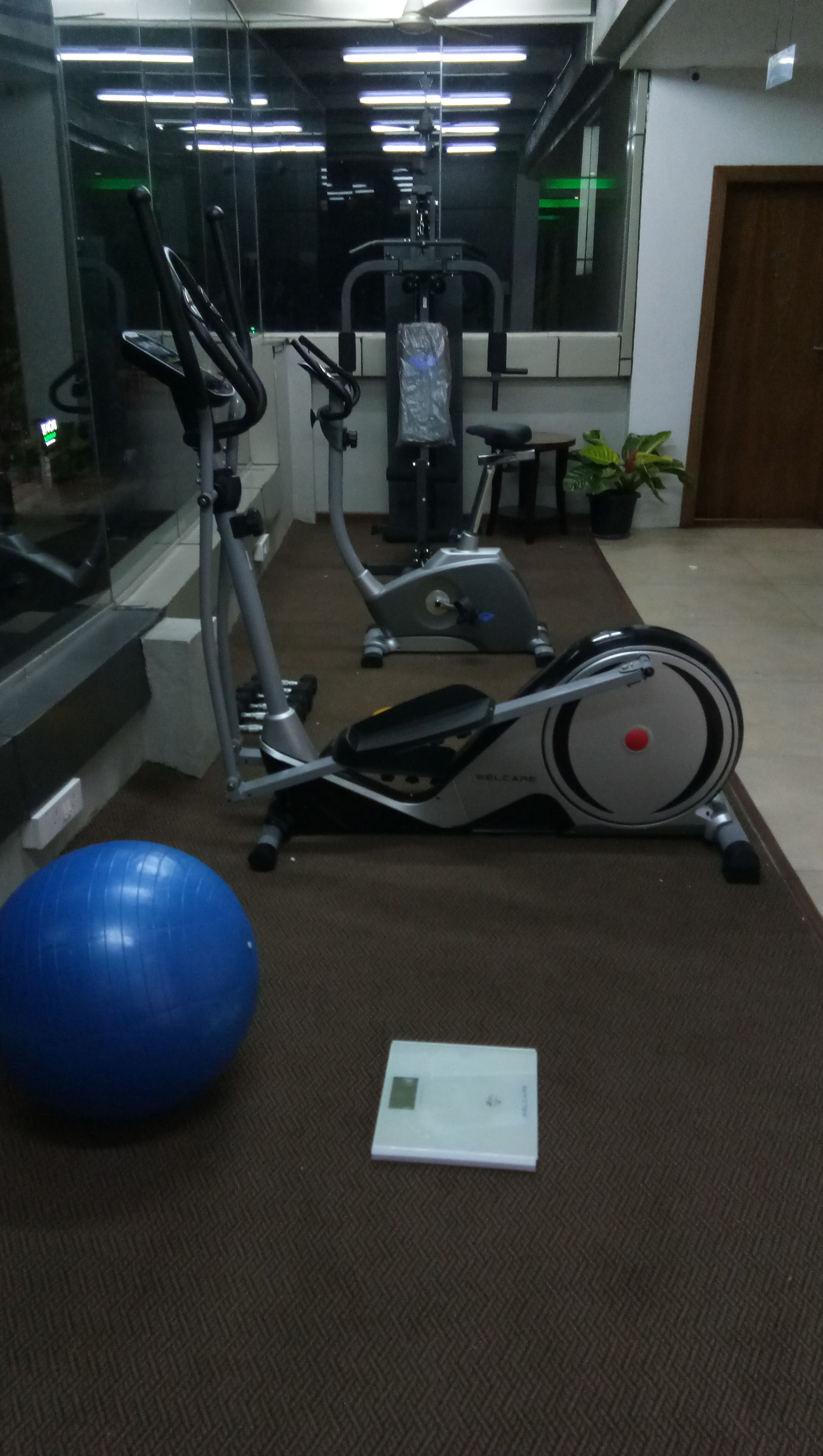 A gym with exercise equipment including a stationary bike, elliptical, and weights.