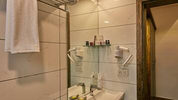 A bathroom with a sink, mirror, towel rack, and a shower area.