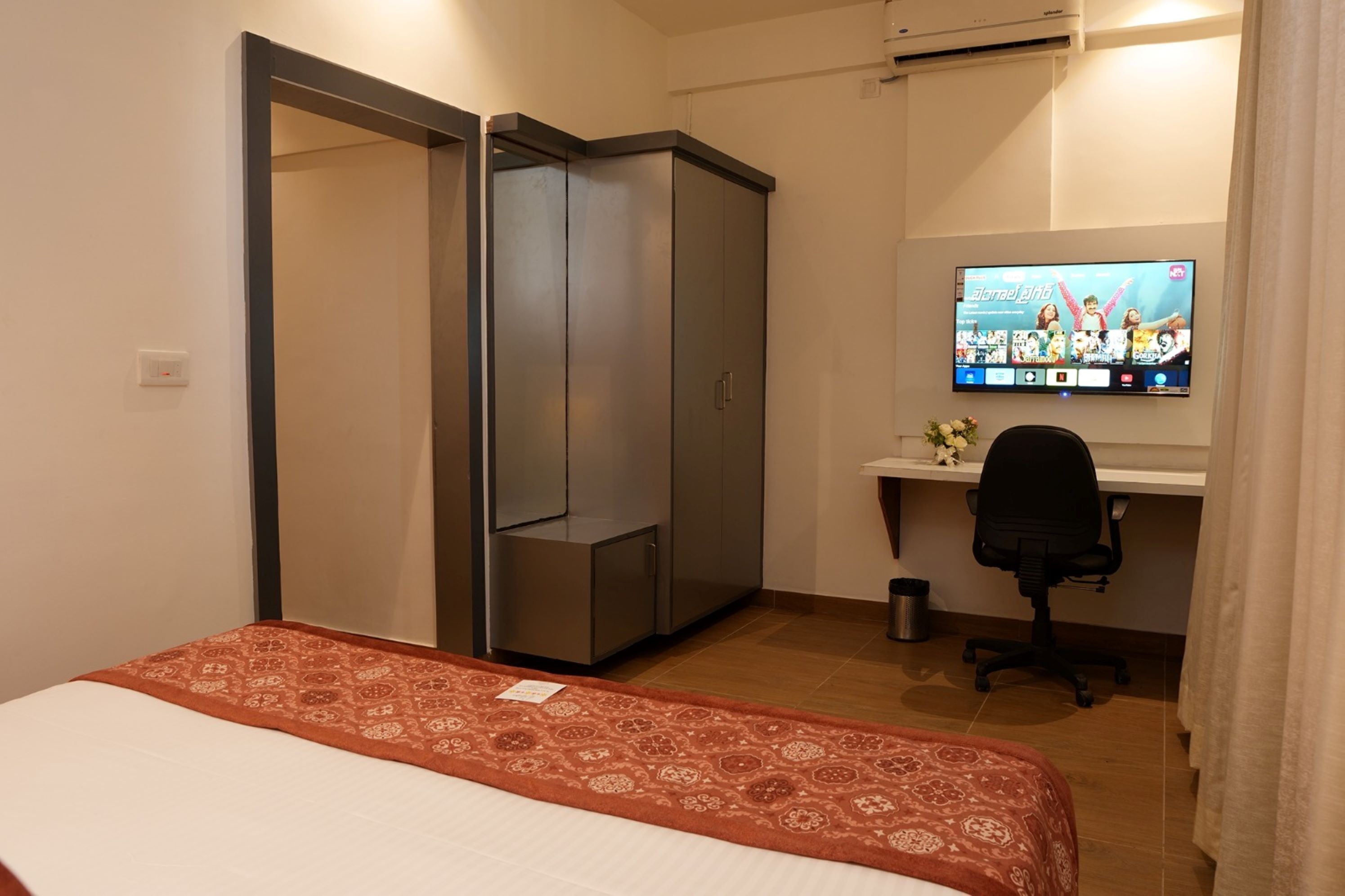 A bedroom with a bed, a desk, a chair, a TV, and a wardrobe.