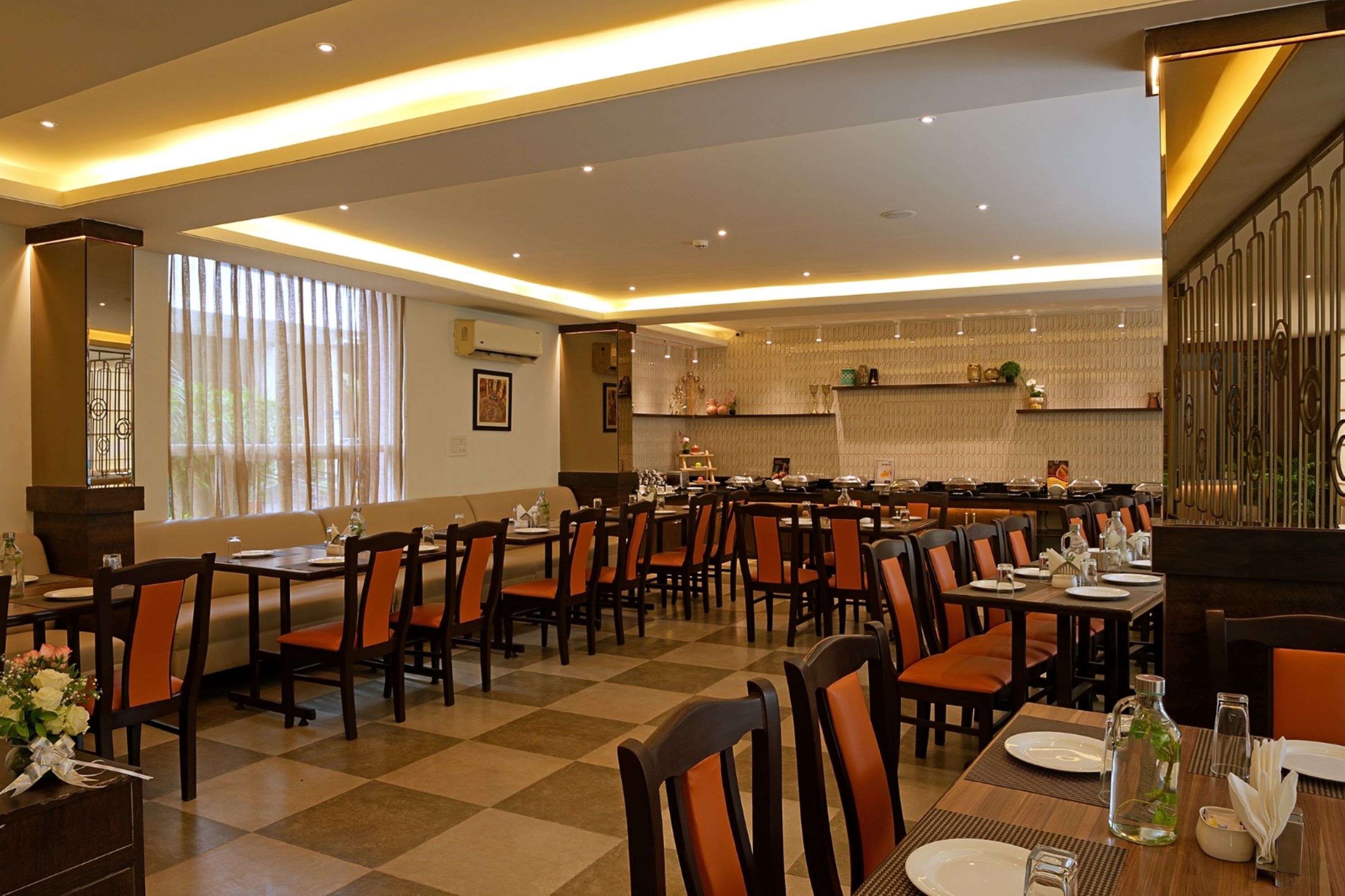 A restaurant with multiple dining tables and chairs, a checkered floor, and a warm, well-lit interior.