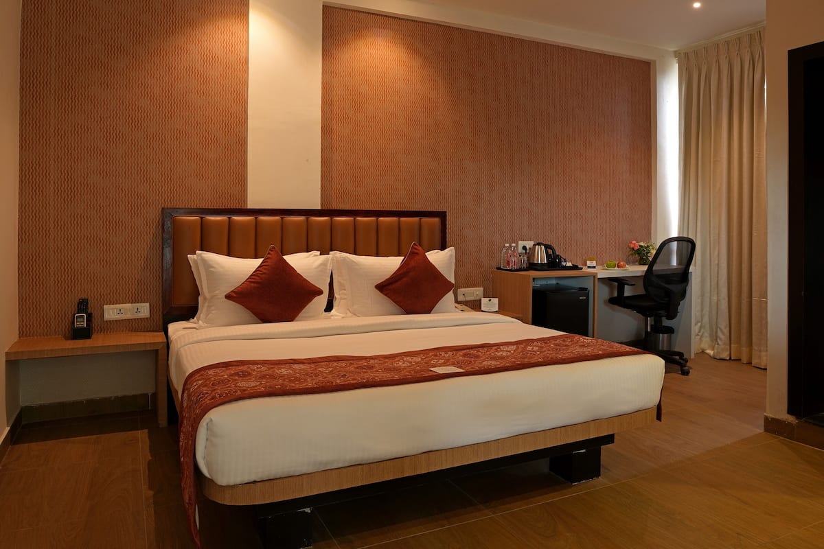Ein Hotelzimmer mit einem großen Bett, einem Schreibtisch, einem Sessel und einer kleinen Küchenzeile.