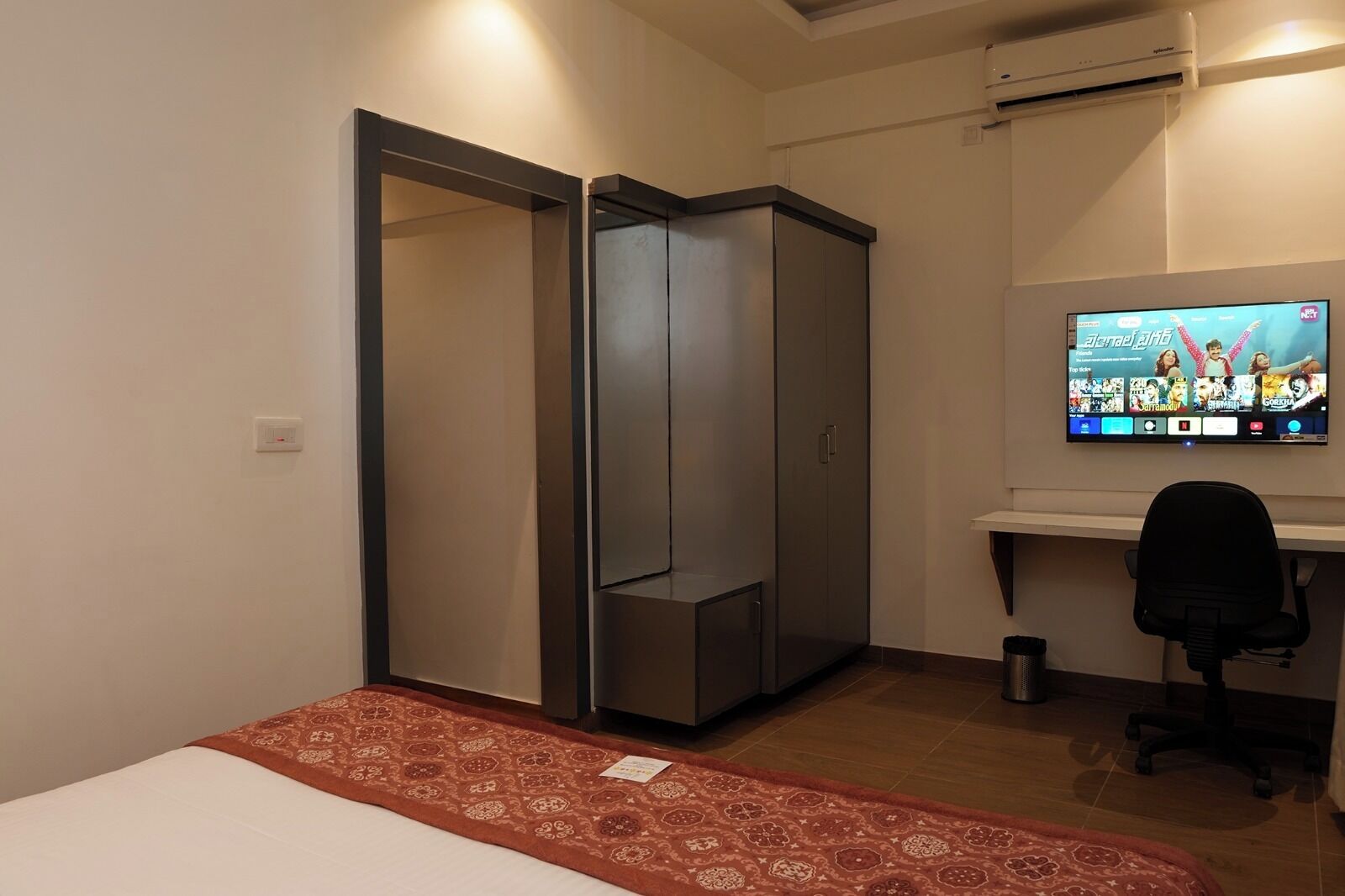 Een slaapkamer met een bed, een televisie, een bureau en een kledingkast.