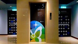 Een moderne lift met een digitaal scherm en een kleurrijk geometrisch patroon op de deur.